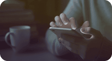Close-up of hands using a phone in the dark